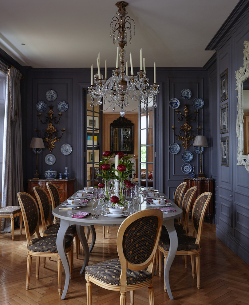 This is an example of a large traditional separate dining room in London with blue walls, medium hardwood floors and brown floor.
