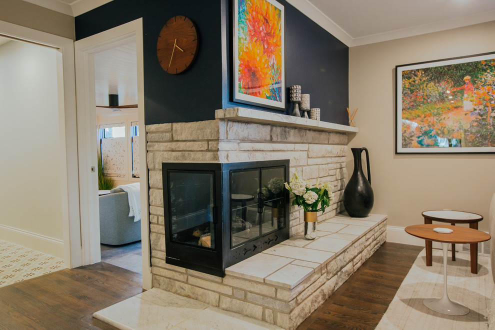 This is an example of an expansive transitional open concept living room in Denver with grey walls, medium hardwood floors, a corner fireplace, a stone fireplace surround, a wall-mounted tv and brown floor.