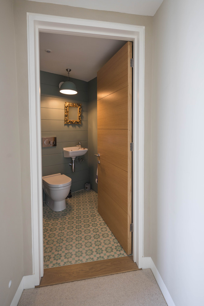 На фото: туалет среднего размера в современном стиле с унитазом-моноблоком, зелеными стенами, полом из керамогранита, подвесной раковиной и подвесной тумбой с