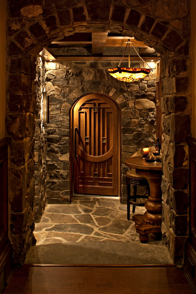 This is an example of a large traditional wine cellar in Calgary with terra-cotta floors, display racks and grey floor.