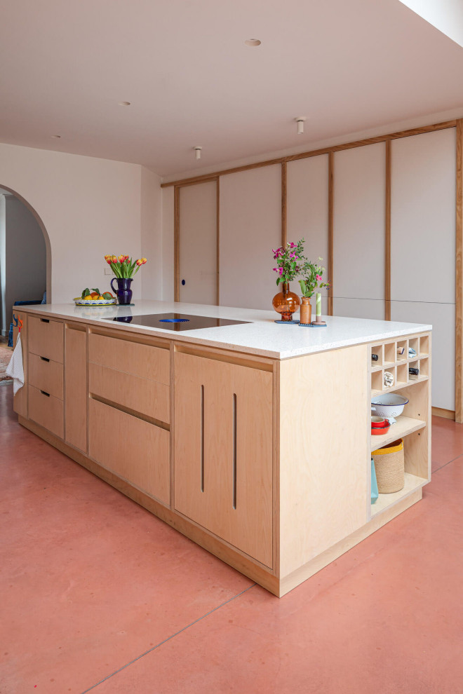 На фото: большая параллельная кухня-гостиная в современном стиле с плоскими фасадами, светлыми деревянными фасадами, бетонным полом, островом и розовым полом с