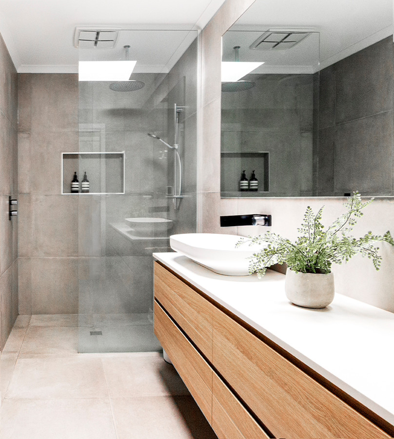Photo of a large contemporary master bathroom in Geelong with a freestanding tub, an open shower, gray tile, cement tile, grey walls, cement tiles, grey floor, an open shower, flat-panel cabinets, medium wood cabinets, a vessel sink, engineered quartz benchtops and white benchtops.