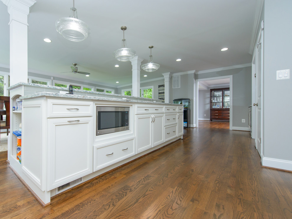 Kitchen - large transitional l-shaped dark wood floor and brown floor kitchen idea in Baltimore with a farmhouse sink, recessed-panel cabinets, white cabinets, quartz countertops, gray backsplash, subway tile backsplash, stainless steel appliances and an island