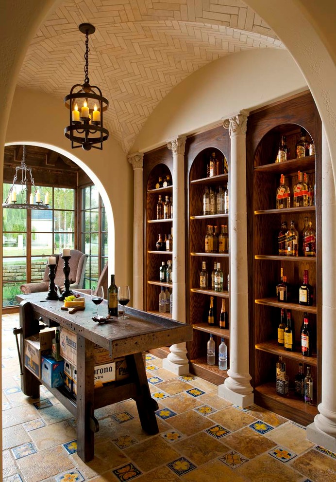 This is an example of a mid-sized mediterranean wine cellar in Dallas with travertine floors and display racks.