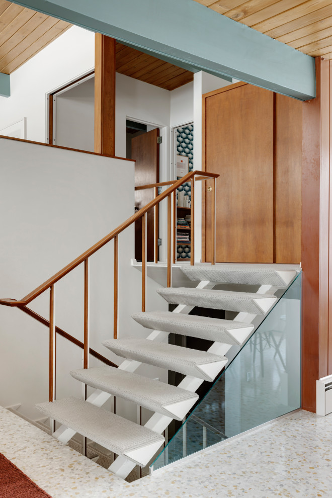 На фото: лестница на больцах, среднего размера в стиле ретро с ступенями с ковровым покрытием и деревянными перилами