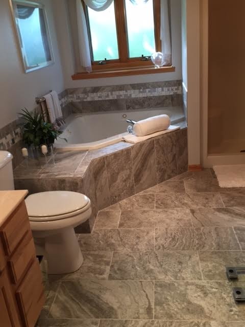 Drop-in bathtub - mid-sized transitional master gray tile and porcelain tile porcelain tile drop-in bathtub idea in Milwaukee with raised-panel cabinets, medium tone wood cabinets, a two-piece toilet and white walls