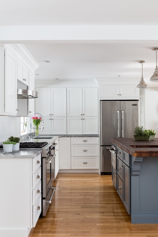 Photo of a small transitional l-shaped eat-in kitchen in Boston with an undermount sink, shaker cabinets, white cabinets, granite benchtops, white splashback, mosaic tile splashback, stainless steel appliances, light hardwood floors and with island.