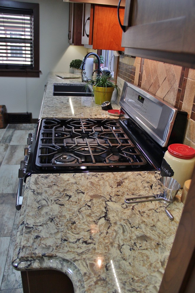 Inspiration for a mid-sized transitional galley ceramic tile enclosed kitchen remodel with an undermount sink, shaker cabinets, medium tone wood cabinets, quartz countertops, beige backsplash, stone tile backsplash, stainless steel appliances and a peninsula