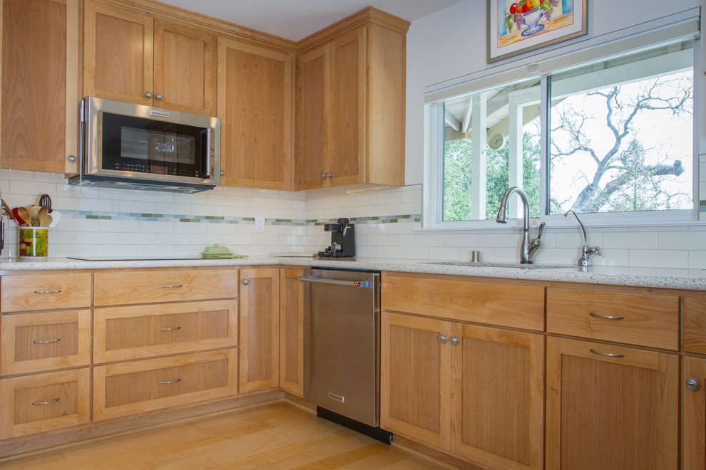 Large traditional l-shaped eat-in kitchen in San Luis Obispo with recessed-panel cabinets, light wood cabinets, ceramic splashback, stainless steel appliances, light hardwood floors, with island, a drop-in sink, granite benchtops and beige splashback.