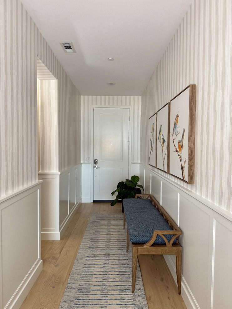 Example of a mid-sized transitional medium tone wood floor, brown floor and wainscoting foyer design in Orange County with multicolored walls and a white front door