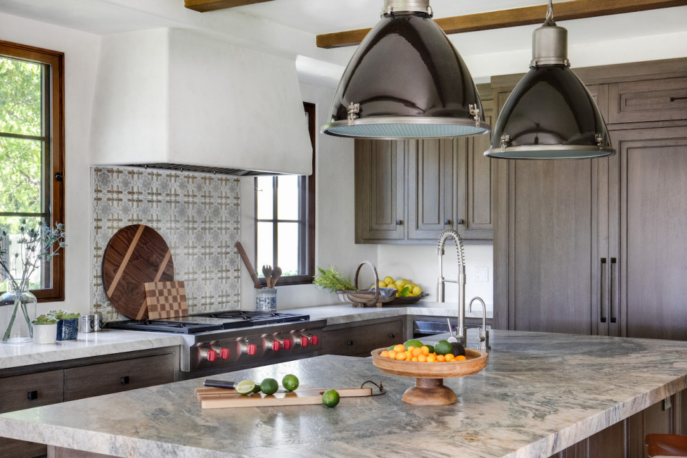 Design ideas for a large mediterranean u-shaped eat-in kitchen in Orange County with a farmhouse sink, raised-panel cabinets, medium wood cabinets, limestone benchtops, blue splashback, ceramic splashback, panelled appliances, travertine floors, with island, beige floor and grey benchtop.