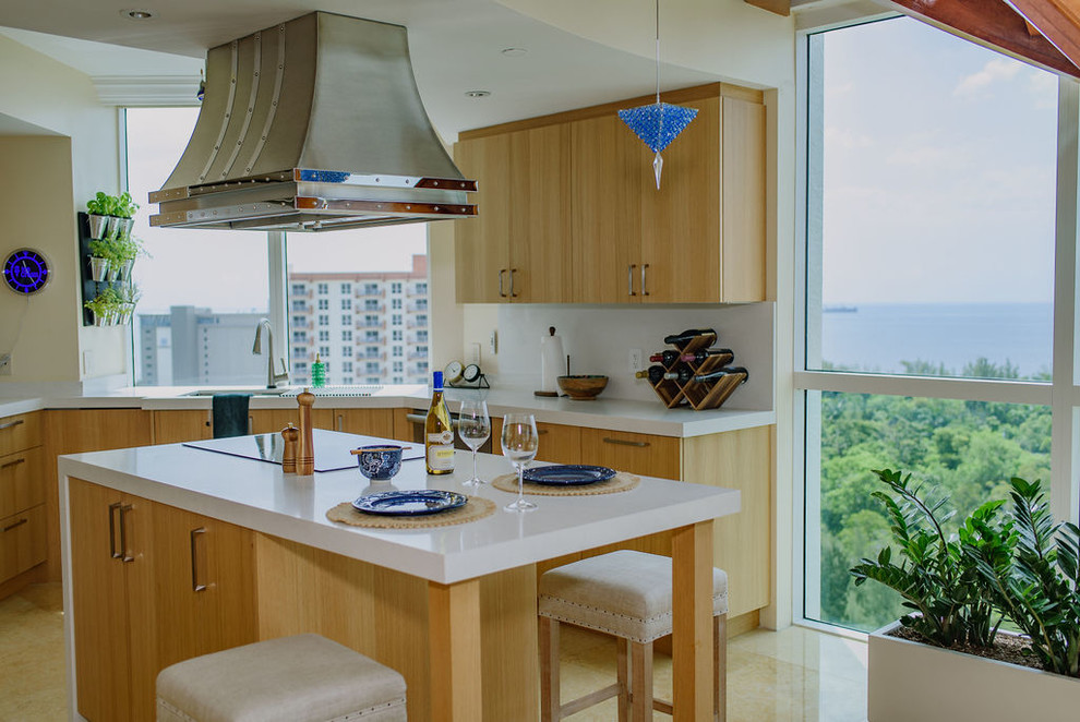 Inspiration for a mid-sized transitional u-shaped porcelain tile and beige floor open concept kitchen remodel in Miami with flat-panel cabinets, light wood cabinets, an island, an undermount sink, quartz countertops, white backsplash, stainless steel appliances and white countertops