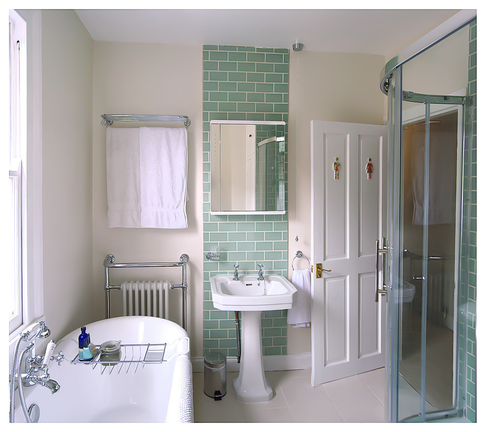 Photo of a small contemporary family bathroom in London with white cabinets, a claw-foot bath, a corner shower, a two-piece toilet, green tiles, ceramic tiles, white walls, porcelain flooring and a pedestal sink.