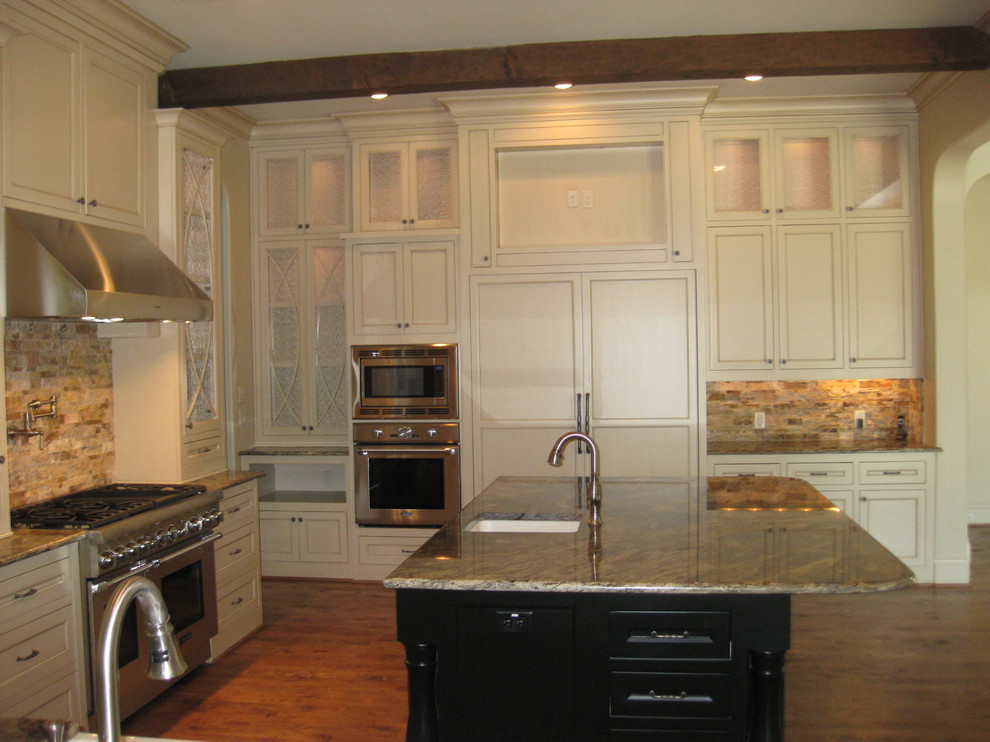 Large transitional u-shaped medium tone wood floor enclosed kitchen photo in Dallas with a farmhouse sink, recessed-panel cabinets, yellow cabinets, granite countertops, beige backsplash, stone tile backsplash, white appliances and an island