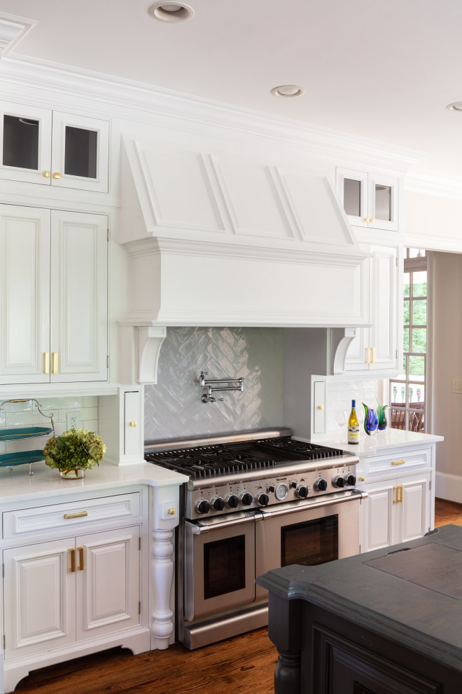 Large transitional u-shaped dark wood floor and brown floor eat-in kitchen photo in Atlanta with a farmhouse sink, recessed-panel cabinets, white cabinets, quartz countertops, white backsplash, ceramic backsplash, stainless steel appliances, an island and white countertops