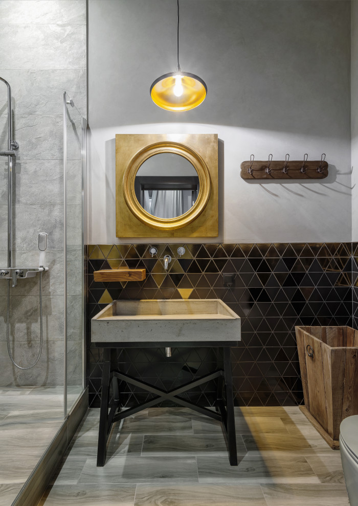 Photo of an industrial bathroom in Other with black tile, grey walls, a single vanity and a console sink.