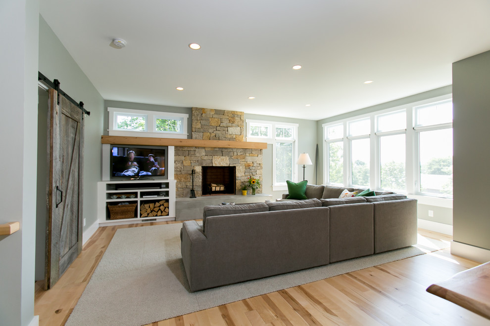 Design ideas for a mid-sized country open concept family room in Other with grey walls, light hardwood floors, a standard fireplace, a stone fireplace surround and a built-in media wall.