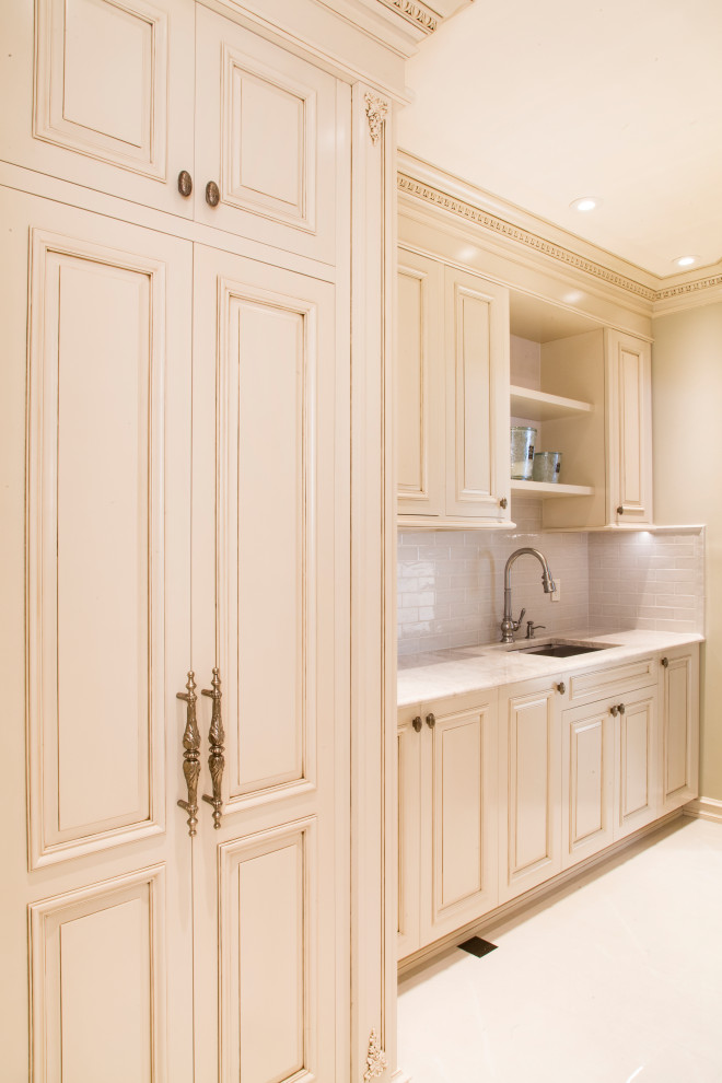 Photo of a mid-sized traditional single-wall dedicated laundry room in New York with shaker cabinets, beige cabinets, quartz benchtops, white splashback, beige walls, ceramic floors, an integrated washer and dryer, white floor and beige benchtop.