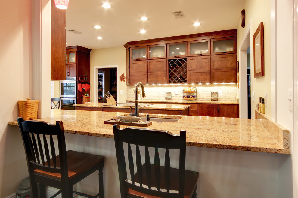 Inspiration for a transitional eat-in kitchen remodel in Miami with an undermount sink, shaker cabinets, brown cabinets, granite countertops, beige backsplash, stone tile backsplash and stainless steel appliances