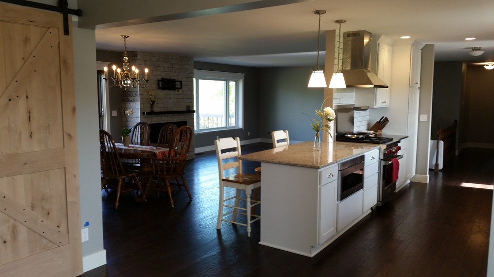 Eat-in kitchen - transitional galley dark wood floor eat-in kitchen idea with white cabinets, granite countertops, white backsplash, subway tile backsplash and stainless steel appliances