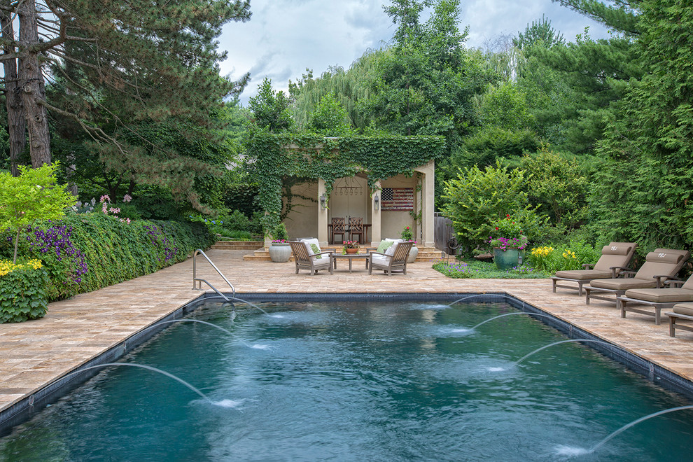 Photo of a large traditional backyard rectangular lap pool in Omaha with a water feature and natural stone pavers.