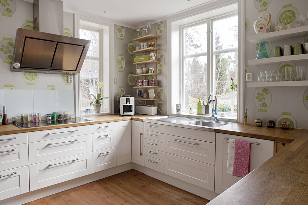 Photo of a mid-sized eclectic u-shaped kitchen in Stockholm with wood benchtops, no island and recessed-panel cabinets.