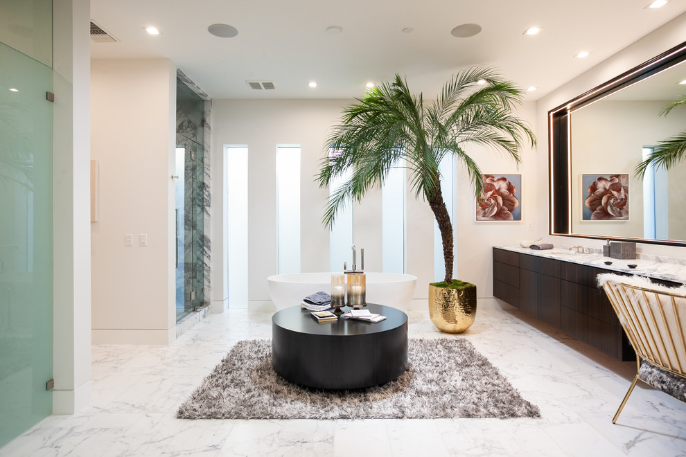 Photo of an expansive contemporary master bathroom in Orange County with flat-panel cabinets, dark wood cabinets, a freestanding tub, an alcove shower, gray tile, marble, beige walls, marble floors, an undermount sink, marble benchtops, white floor, a hinged shower door and grey benchtops.