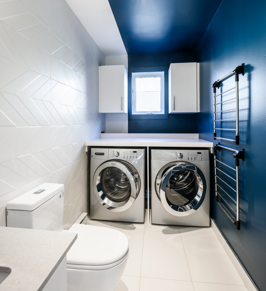 This is an example of a mid-sized modern utility room in Montreal with an undermount sink, flat-panel cabinets, white cabinets, laminate benchtops, white splashback, ceramic splashback, blue walls, ceramic floors, a side-by-side washer and dryer, white floor and white benchtop.
