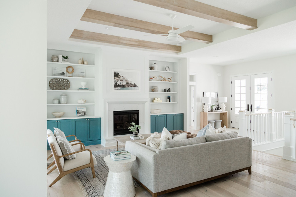 Inspiration for a mid-sized living room in Los Angeles with white walls, light hardwood floors, a standard fireplace, a stone fireplace surround, white floor and exposed beam.