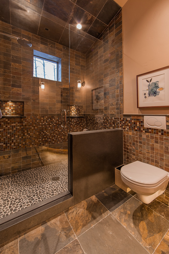 This is an example of a country bathroom in Denver with an alcove shower, a wall-mount toilet, brown tile and brown floor.