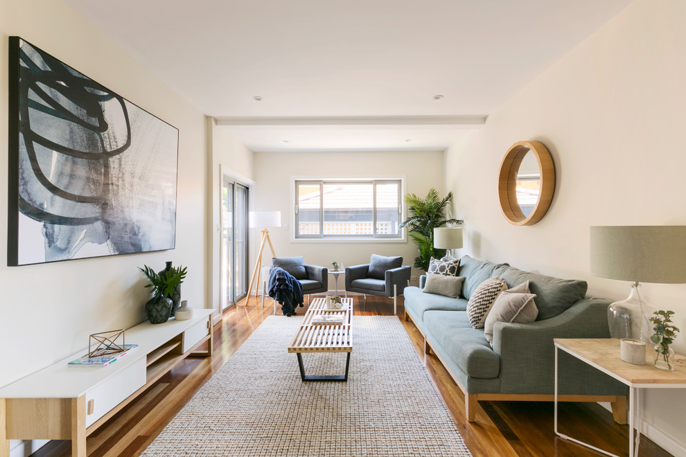 This is an example of a beach style formal enclosed living room in Sydney with beige walls, medium hardwood floors and brown floor.