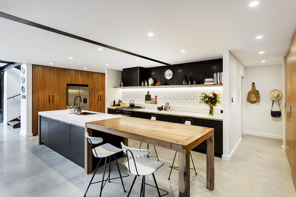 This is an example of an expansive industrial galley open plan kitchen in Sydney with a double-bowl sink, medium wood cabinets, marble benchtops, white splashback, ceramic splashback, stainless steel appliances, concrete floors and with island.