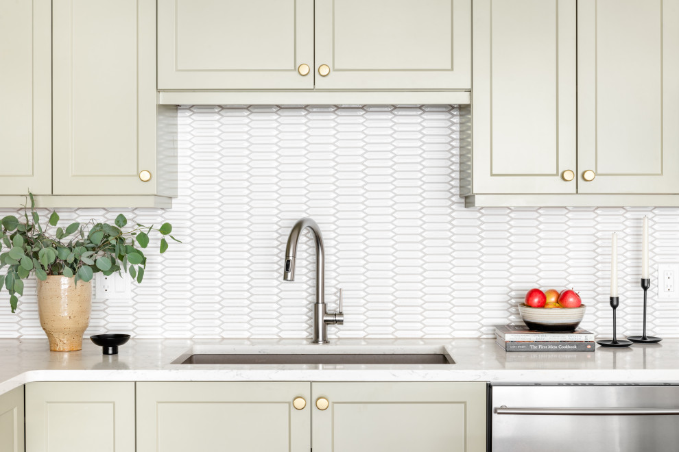 Example of a small transitional brown floor kitchen design with shaker cabinets, green cabinets, white backsplash, stainless steel appliances, an island and white countertops