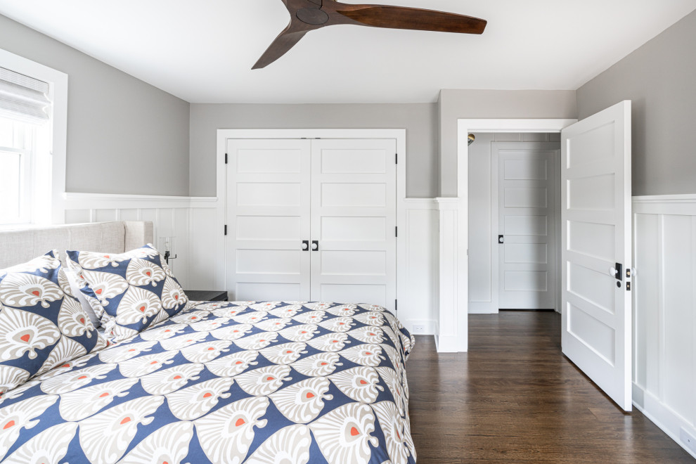 На фото: гостевая спальня (комната для гостей) в стиле неоклассика (современная классика) с серыми стенами, темным паркетным полом, коричневым полом и панелями на стенах
