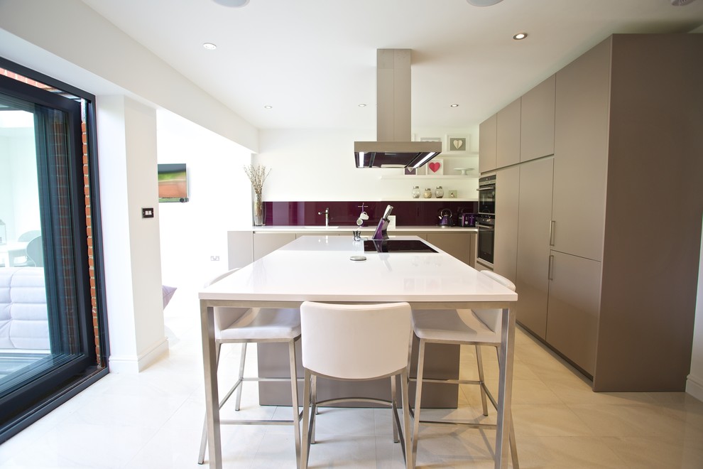 Mid-sized contemporary u-shaped eat-in kitchen in Hampshire with an integrated sink, flat-panel cabinets, grey cabinets, solid surface benchtops, blue splashback, glass sheet splashback, stainless steel appliances, porcelain floors and with island.