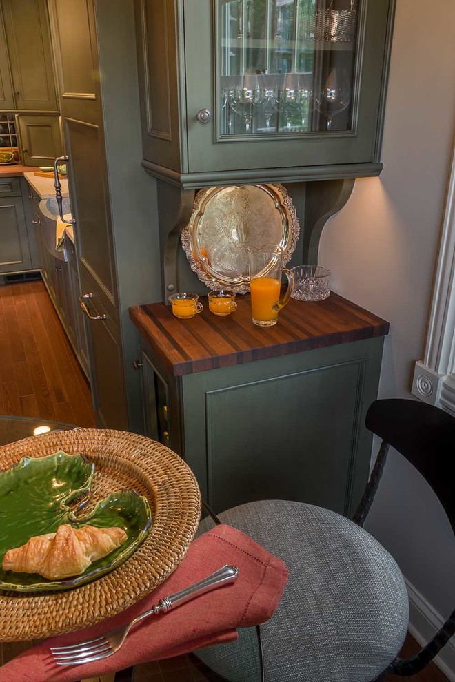 Small country l-shaped eat-in kitchen in Chicago with a farmhouse sink, flat-panel cabinets, green cabinets, limestone benchtops, multi-coloured splashback, porcelain splashback, stainless steel appliances, medium hardwood floors, with island and brown floor.