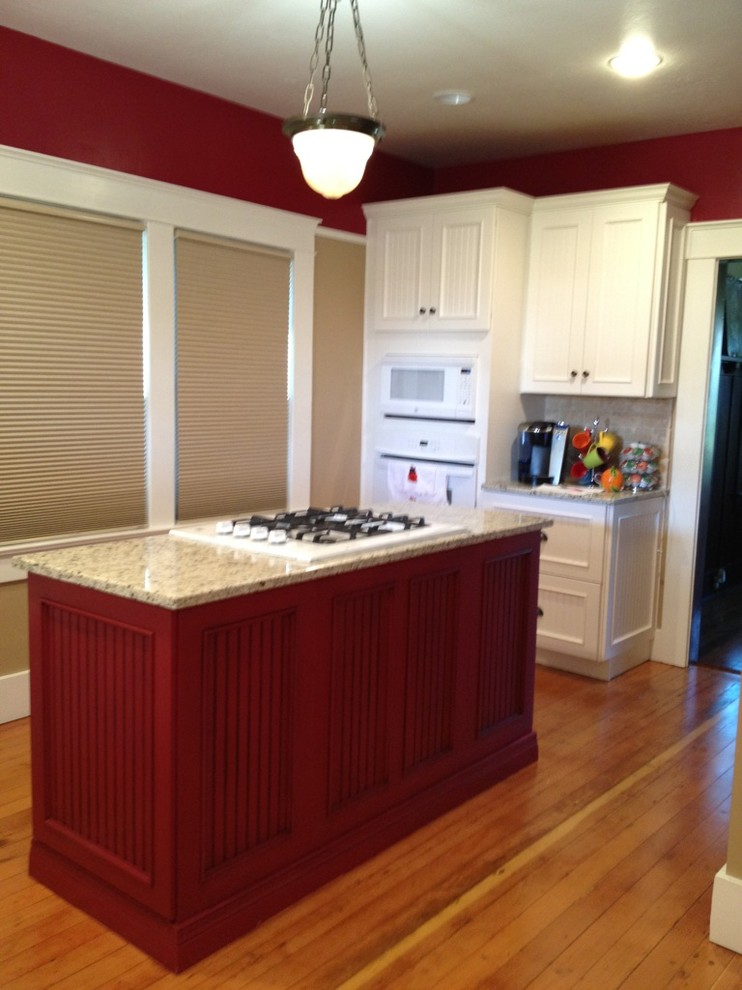 Photo of a small country u-shaped separate kitchen in Other with a farmhouse sink, louvered cabinets, red cabinets, granite benchtops, beige splashback, subway tile splashback, white appliances, medium hardwood floors and with island.