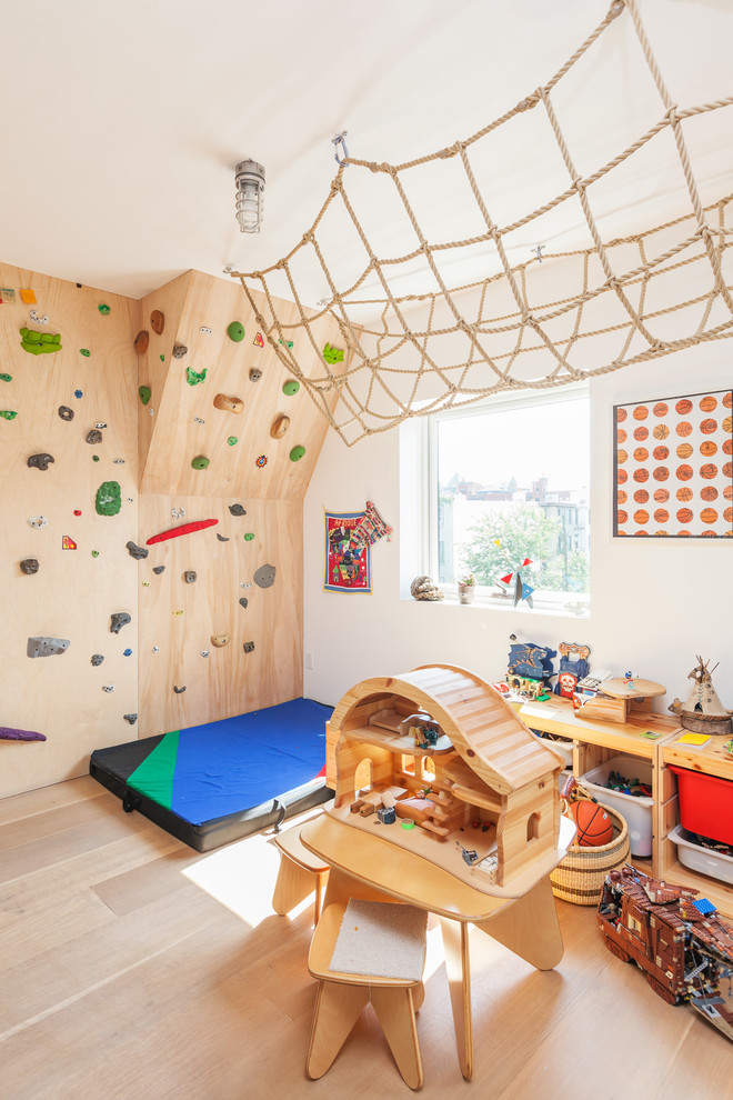 This is an example of a contemporary gender-neutral kids' playroom for kids 4-10 years old in New York with white walls and light hardwood floors.