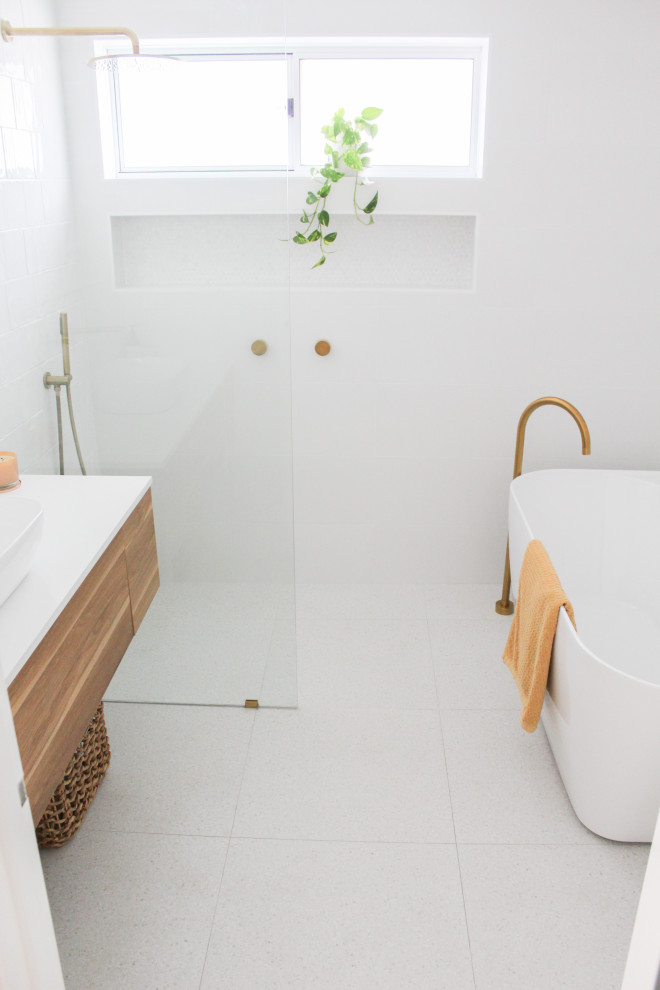 Источник вдохновения для домашнего уюта: главная ванная комната среднего размера в стиле модернизм с плоскими фасадами, светлыми деревянными фасадами, отдельно стоящей ванной, душевой комнатой, белой плиткой, керамической плиткой, белыми стенами, полом из керамогранита, настольной раковиной, столешницей из искусственного кварца, серым полом, открытым душем, белой столешницей, тумбой под одну раковину и подвесной тумбой