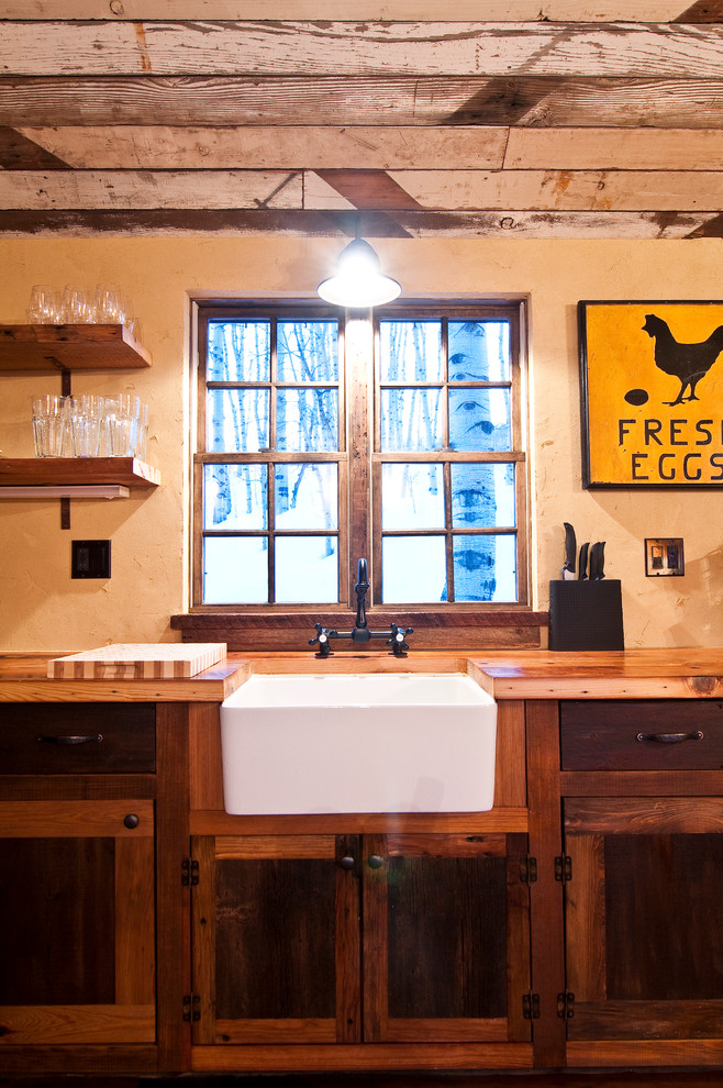 Inspiration for a small rustic l-shaped medium tone wood floor open concept kitchen remodel in Denver with a farmhouse sink, shaker cabinets, medium tone wood cabinets, wood countertops, yellow walls and no island