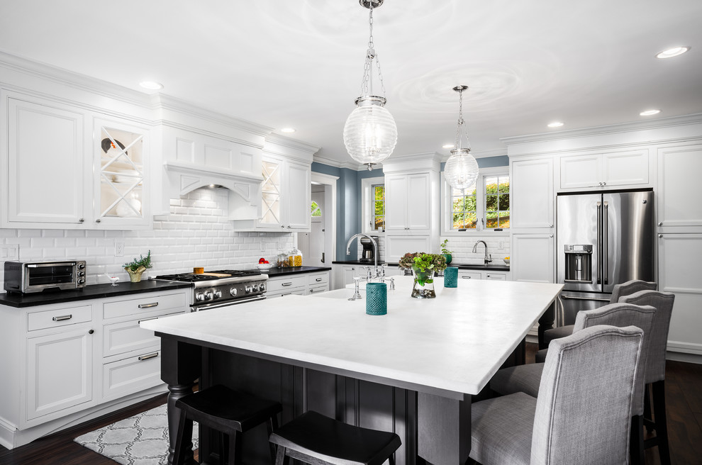 Large traditional l-shaped eat-in kitchen in Philadelphia with a farmhouse sink, recessed-panel cabinets, white cabinets, soapstone benchtops, white splashback, subway tile splashback, stainless steel appliances, dark hardwood floors and with island.