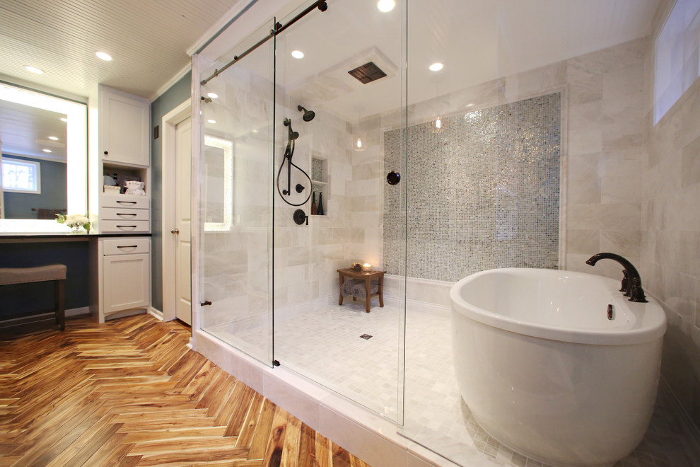 Large contemporary master bathroom in Minneapolis with shaker cabinets, white cabinets, a freestanding tub, an alcove shower, beige tile, ceramic tile, blue walls, medium hardwood floors, an undermount sink, brown floor and a sliding shower screen.
