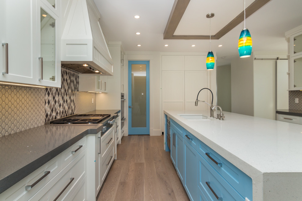 This is an example of a large contemporary galley eat-in kitchen in Calgary with a double-bowl sink, shaker cabinets, white cabinets, quartz benchtops, grey splashback, ceramic splashback, panelled appliances, light hardwood floors, with island and grey floor.