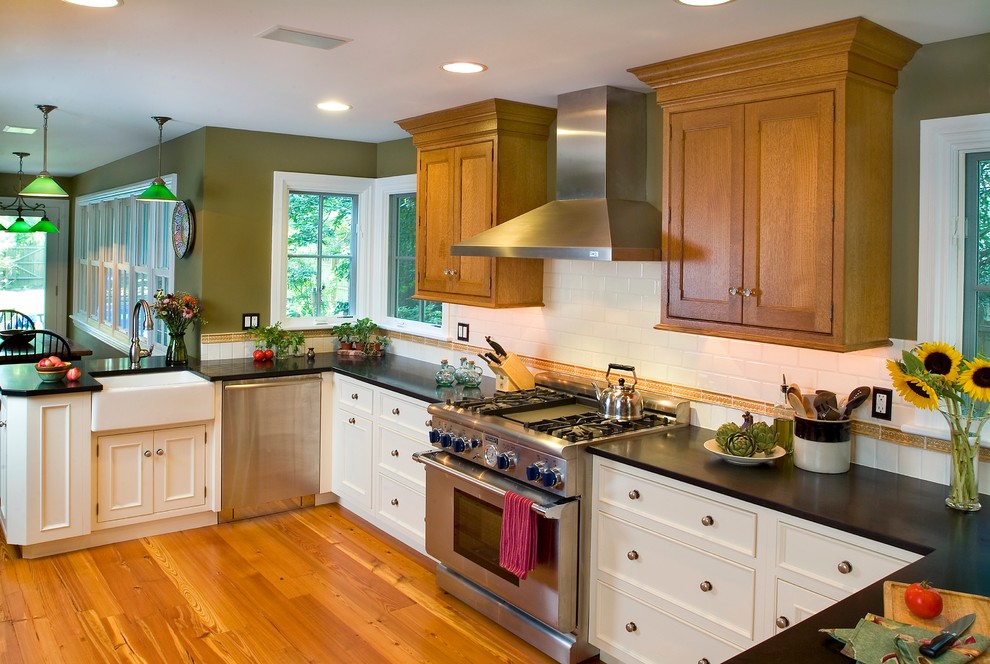 Photo of a mid-sized arts and crafts u-shaped separate kitchen in Philadelphia with a farmhouse sink, beaded inset cabinets, white cabinets, granite benchtops, white splashback, ceramic splashback, stainless steel appliances, medium hardwood floors and no island.