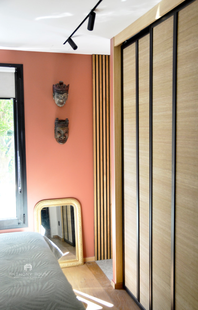 Idee per una piccola camera matrimoniale bohémian con pareti arancioni, pavimento in legno massello medio, pavimento marrone e carta da parati