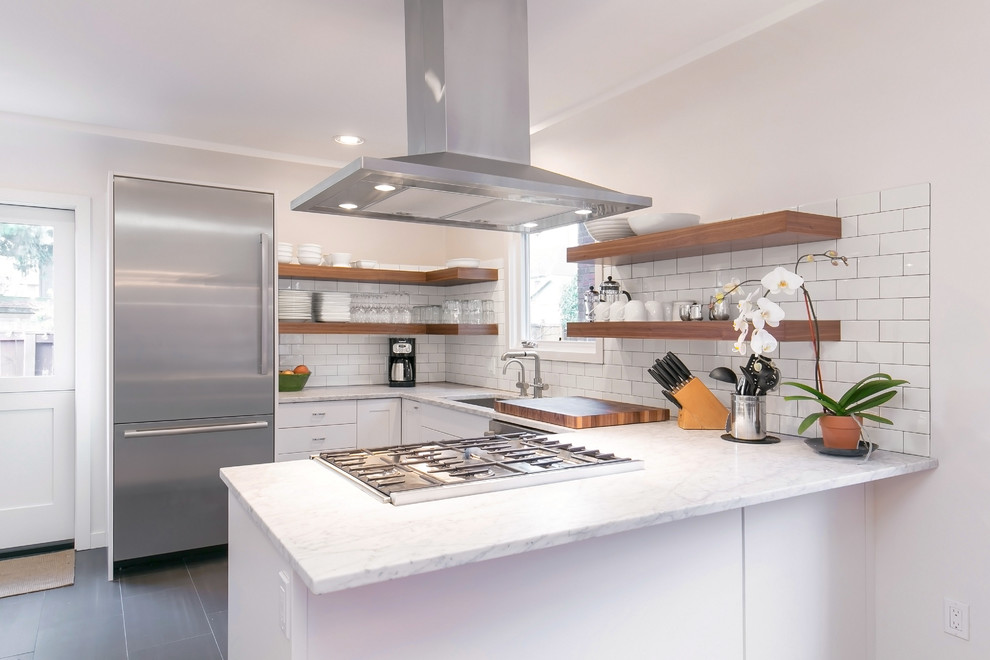 Photo of an arts and crafts l-shaped eat-in kitchen in Seattle with a single-bowl sink, open cabinets, marble benchtops, white splashback, ceramic splashback, stainless steel appliances, ceramic floors, a peninsula and grey floor.