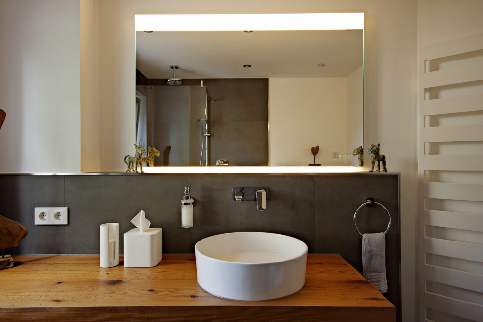 Duschbad With flächenbündigen Schrankfronten, weißen Schränken, bodengleicher Dusche, Wandtoilette mit Spülkasten, grauen Fliesen, Steinfliesen, weißer Wandfarbe, Kalkstein, Aufsatzwaschbecken, Waschtisch aus Holz, grauem Boden, offener Dusche and beiger Waschtischplatte in Munich