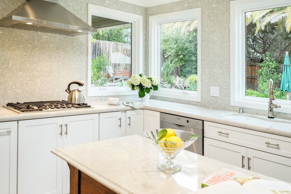 Example of a large transitional u-shaped limestone floor eat-in kitchen design with an undermount sink, shaker cabinets, white cabinets, marble countertops, metallic backsplash, mosaic tile backsplash, stainless steel appliances and an island