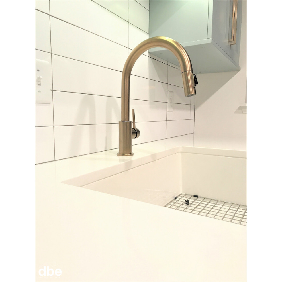 Small transitional galley vinyl floor and brown floor kitchen photo with a farmhouse sink, shaker cabinets, blue cabinets, quartz countertops, white backsplash, subway tile backsplash, stainless steel appliances, no island and white countertops