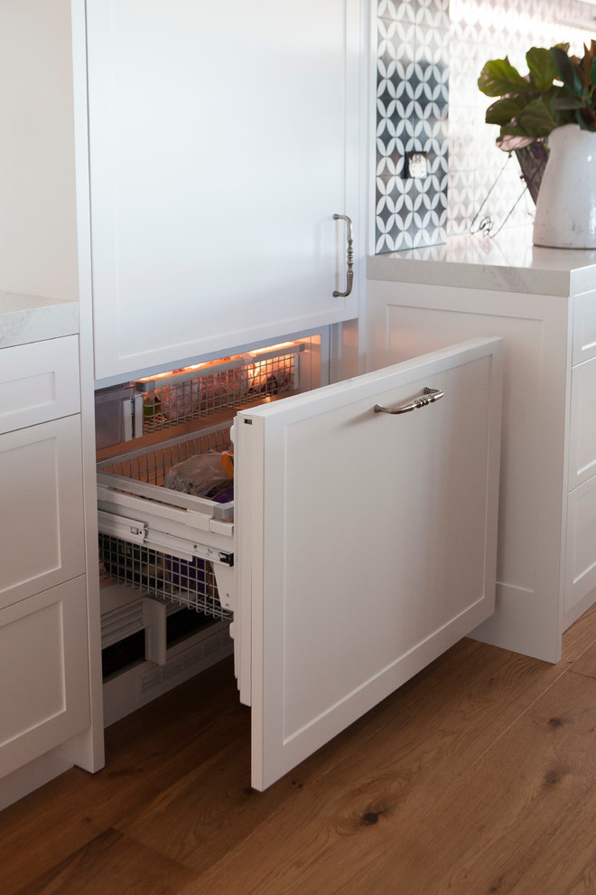 Photo of a large transitional galley eat-in kitchen in Sydney with a double-bowl sink, shaker cabinets, white cabinets, quartz benchtops, brown splashback, ceramic splashback, stainless steel appliances, medium hardwood floors and with island.